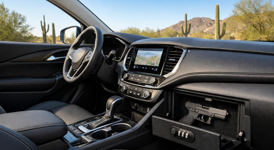 Interior of a modern car parked in a desert setting with a handgun securely stored inside a locked compartment.